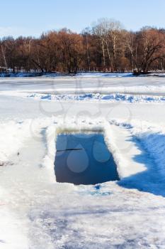 ice-hole in frozen pond in sunny winter day