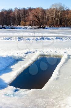 ice-hole in frozen river in sunny winter day