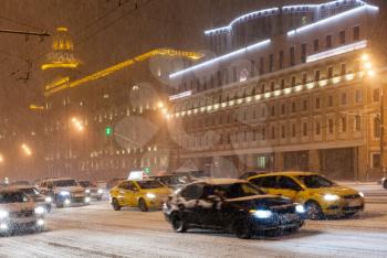 snowfall in night city - street traffic under snow on Bolshaya Sukharevskaya Square, Moscow