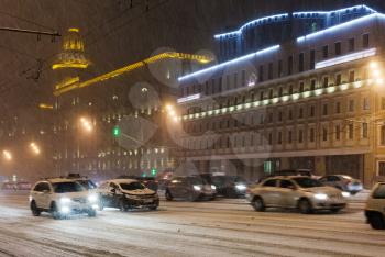 snowfall in night city - cars driving under snow on Bolshaya Sukharevskaya Square, Moscow
