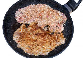 top view of two schnitzels are fried in pan isolated on white background