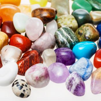 many tumbled natural mineral gemstones close up on white