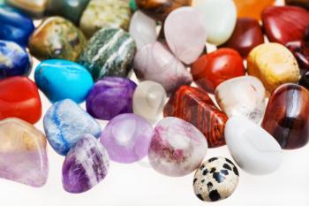 many tumbled natural mineral gem stones close up on white background