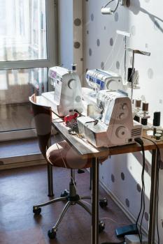 workplace of seamstress at home - sewing machines and serger on table