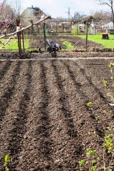 plowed country garden and tiller in village in spring
