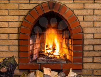 open fire in indoor brick fireplace in country cottage