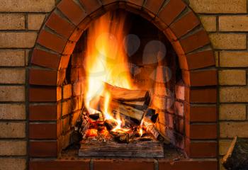 tongues of fire in indoor brick fireplace in country cottage