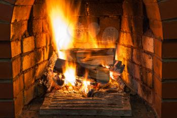 burning wood in brick fireplace in country cottage