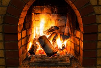 burning wooden logs in fire-box of fireplace in country cottage