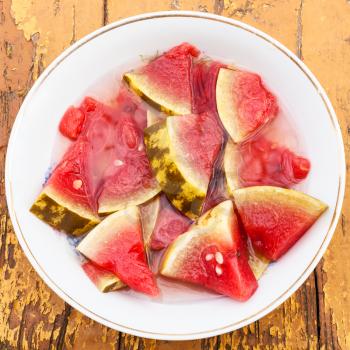 top view of pickled watermelon on white plate on wooden table