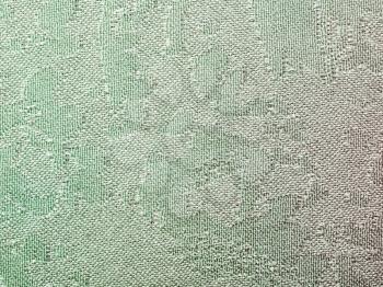 textile background - green batik silk fabric with Jacquard weave pattern of threads close up