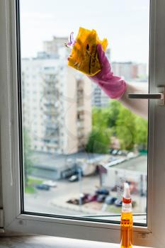washing home window in spring - cleaner cleans window frame by rag in apartment house