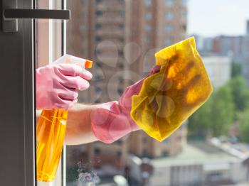 washing home window - washer washes window glass with detergent in apartment house