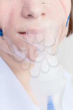 medical inhalation treatment - patient inhales with face mask of modern jet nebuliser close up