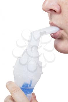 medical inhalation treatment - mouthpiece of modern jet nebuliser in lips of woman isolated on white background