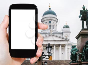 travel concept - tourist photographs Cathedral in Helsinki Finland (St Nicholas Church) on smartphone with cut out screen with blank place for advertising