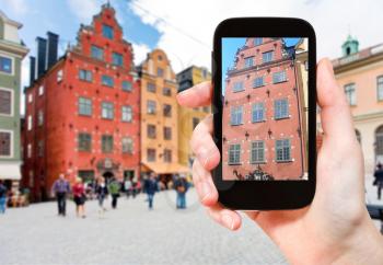 travel concept - tourist photographs facade of old historical house on stortorget square in stockholm, sweden on smartphone