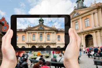 travel concept - tourist photographs facade of swedish academy palace on stortorget square in stockholm on tablet pc