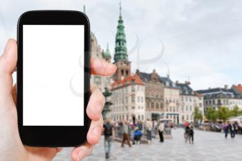 travel concept - tourist photographs Amagertorv the central square in Copenhagen, Denmark on smartphone with cut out screen with blank place for advertising