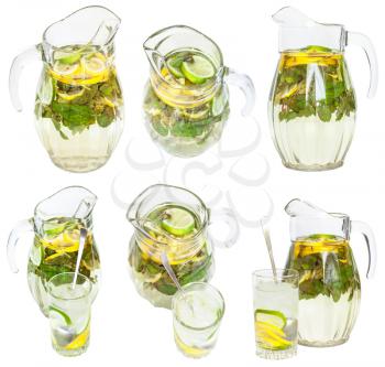 set from glass pitchers and tumblers with natural lemonade drink from lemon, lime, mint isolated on white background