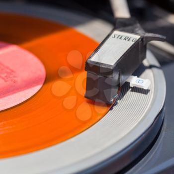 tonearm of turntable on orange vinyl record close up