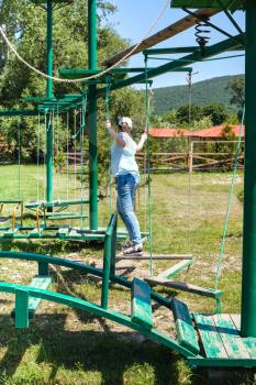 girl overcomes an outdoor obstacle course in sunny summer day