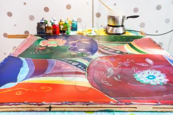 manufacturing steps of hot batik in the workshop - silk fabric with final fourth layer of paints and wax