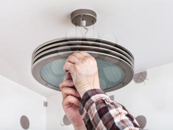 Electrician fixes round ceiling light in room