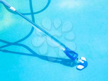 cleaning bottom of swimming pool by underwater vacuum cleaner