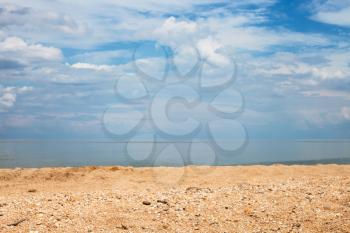Foreground focus - sand and shelly beach and white clouds over sea. Coastline of Sea of Azov, Temryuk bay, Golubitskaya resort, Taman peninsula, Kuban, Russia