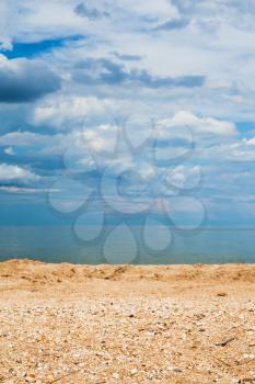 Foreground focus - sand and shelly beach and dark blue clouds over sea. Coastline of Sea of Azov, Temryuk bay, Golubitskaya resort, Taman peninsula, Kuban, Russia