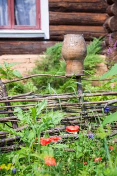 rural scenery - wattle fence with clay pot and old country cottage