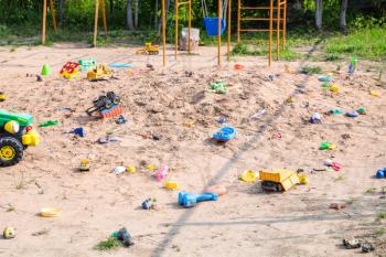 Forgotten toys in outdoor sand playground in summer day