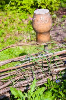 rural scenery - wattle hurdle with old clay pot