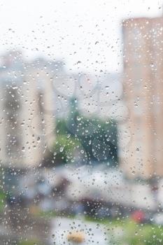 rain drops on window and blurred skyline on background