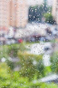 rain drops on window and blurred cityscape on background