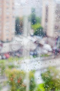 rain drops on window glass and blurred cityscape on background