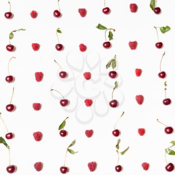 many raspberries and cherries arranged on square white background