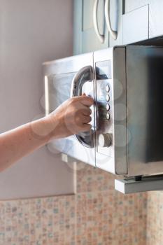 hand closes door of microwave oven for heating food