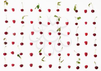 lot of raspberries and cherries arranged on white background
