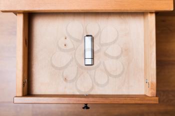 top view of closed flash drive in open drawer of nightstand
