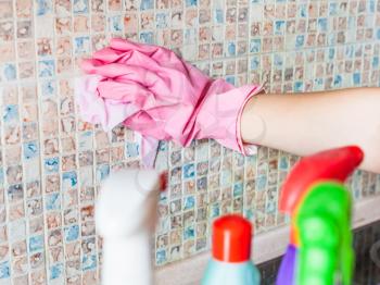House cleaning - hand in glove washes ceramic tiles on kitchen wall