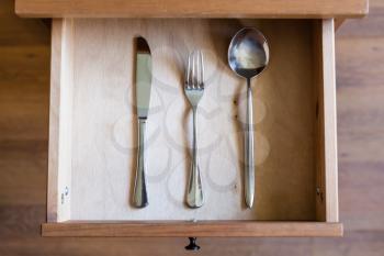 top view of knife, fork, spoon in open drawer of nightstand