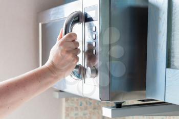 hand closes door of microwave oven for cooking food