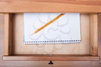 above view of pencil on artistic album in open drawer of nightstand
