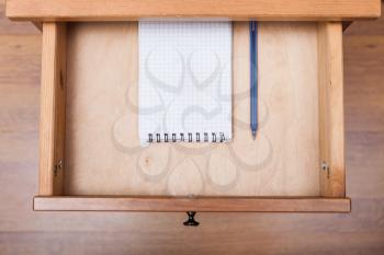 top view of blue pen and squared notebook in open drawer of nightstand