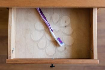 above view of modern toothbrush in open drawer of nightstand