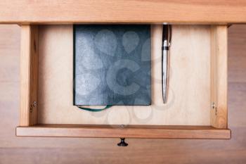 above view of modern pen and notebook in open drawer of nightstand