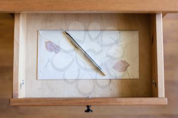 top view of silver pen on vintage envelope in open drawer of nightstand