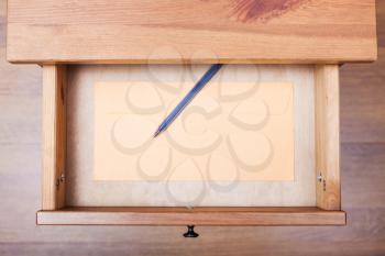 top view of modern pen and envelope in open drawer of nightstand